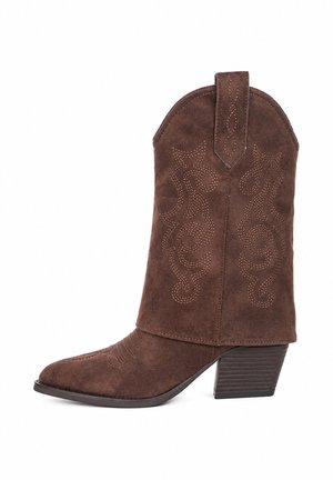 Bruine suède cowboylaars met decoratieve stiksels, puntige neus, aantreklus en gestapelde hak van middelhoogte, zijaanzicht op een witte achtergrond.
