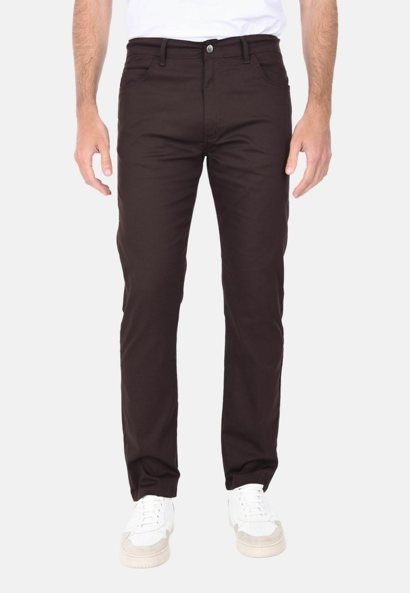 Pantaloni in denim marrone scuro con vestibilità slim, cinque tasche e design pulito. Presentano una chiusura con bottone e passanti per la cintura, abbinati a sneaker bianche.