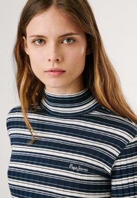 Jūras spēku un balts svītrains augstais kakls ar ribotu tekstūru. Uz krūtīm ir "Pepe Jeans" logo baltiem izšuvumiem.