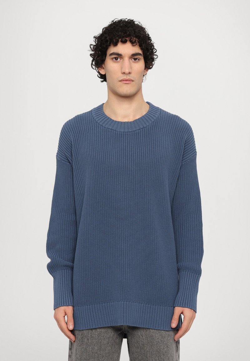 Maglione lavorato a maglia di colore blu ardesia, con scollatura e polsini a coste, vestibilità ampia, tessuto strutturato e silhouette rilassata.