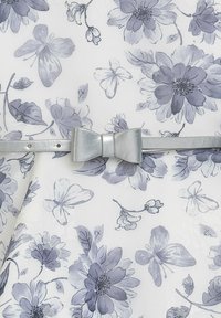 Blumenkleid in Weiß mit grauen und lavendelfarbenen Blüten, ausgestattet mit einem glänzenden silbernen Gürtel mit einer Schleifendetail in der Taille.