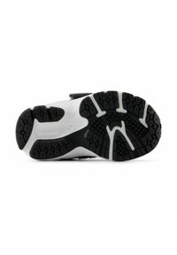 Semelle de chaussure de sport en noir et blanc mettant en avant une surface en caoutchouc texturée avec un motif de sculpture prononcé et un détail de logo.