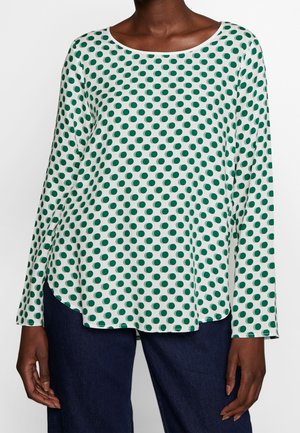 Langärmliges Oberteil in hellgrün mit dunkelgrünen Polka-Dots. Glatter Stoff, Rundhalsausschnitt, seitliche Schlitze und abgerundeter Saum.