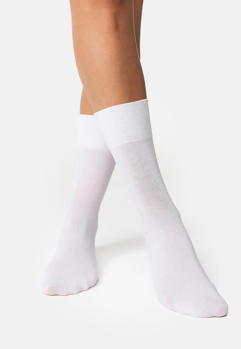 Chaussettes en coton blanches avec un bord côtelé, design à hauteur de cheville et texture lisse. Dotées d'un orteil sans coutures pour plus de confort.