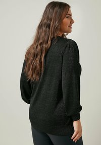 Maglione nero con finitura texture, caratterizzato da maniche a sbuffo e orlo arrotondato. Il materiale include sottili fili metallici per un effetto lucido.