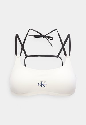 Λευκό αθλητικό σουτιέν με μαύρους ρυθμιζόμενους ιμάντες και κορδόνι στο πίσω μέρος, με το λογότυπο Calvin Klein στο κέντρο μπροστά.
