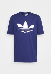 Námořnická modrá bavlněná tričko s krátkým rukávem, s velkým bílým logem trefoil a vodorovnými pruhy na hrudi.