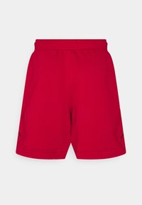 Shorts de sport rouges avec une taille élastique et des poches latérales, présentés sur un fond gris clair uni.