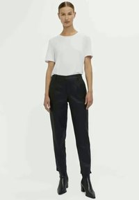 White short-sleeve t-shirt paired with high-waisted black trousers and black heeled boots, presenting a fitted silhouette and smooth texture.