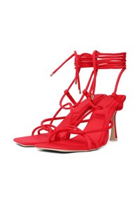 Rote, schicke High-Heelsandalen mit flachen Sohlen, die über mehrere ineinander verwobene Riemen und eine elegante Absatzakzent verfügen. Hergestellt aus weichem Material.