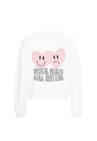 Sudadera blanca con un gran gráfico de dos corazones rosas con caras sonrientes y tristes. El texto dice "LA SALUD MENTAL SIGUE IMPORTANDO" en una fuente negra y en negrita.