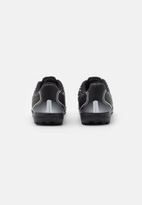 Et par sorte sportsko med hvide geometriske mønstre set fra ryggen på en ensfarvet hvid baggrund.