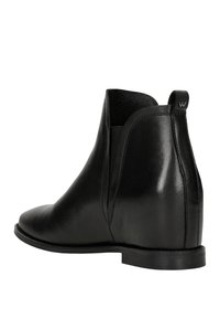 Stivaletti neri in pelle con una texture liscia, pannelli laterali elastici e un tacco basso e piatto, con una piccola etichetta logo sul retro.