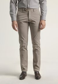 Chinos beige claros hechos de una mezcla de algodón, con un corte recto en la parte delantera, bolsillos laterales y cierre de botón. Llevados con mocasines marrón oscuro.