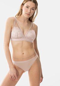 Bralette en dentelle rose clair avec des panneaux en tulle, présentant un design en V, des bretelles ajustables et une culotte sans couture assortie avec une fine taille.