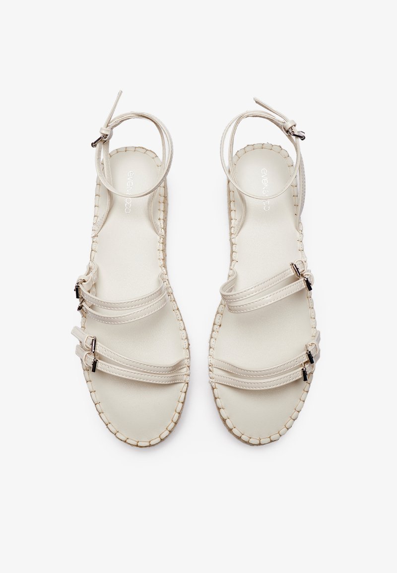 Sandalias de cuero blanco con tres correas y hebillas ajustables, bordes trenzados y una plantilla suave. Diseño minimalista y abierto.