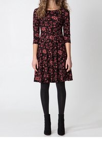 Black floral dress with three-quarter sleeves, featuring red and pink flower patterns, flared skirt, and paired with black ankle boots.