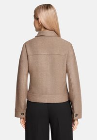 Brązowa kurtka z mieszanki wełny z wyraźnym kołnierzem, długimi rękawami i zapinanymi mankietami. Dopasowany krój z prostym dołem i teksturowanym materiałem.