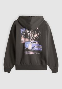 Sweat à capuche noir avec un graphisme d'un loup, pleine lune, éclair et une camionnette bleue sur une route sombre et pluvieuse.