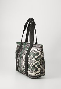 Large tote bag with black and white floral patterns, green accents, reinforced black handles, and a structured design. Durable fabric material.