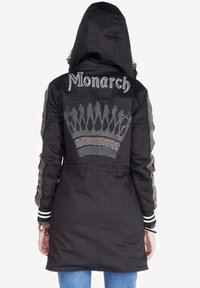Giacca nera con un design a corona e il testo "Monarch" ricamato sul retro, con accenti argentati sulle maniche e sul cappuccio.