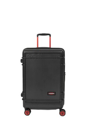 Valise rigide à roulettes noire avec une surface texturée, roues rouges et poignée rétractable. Présente le logo Eastpak à l'avant.