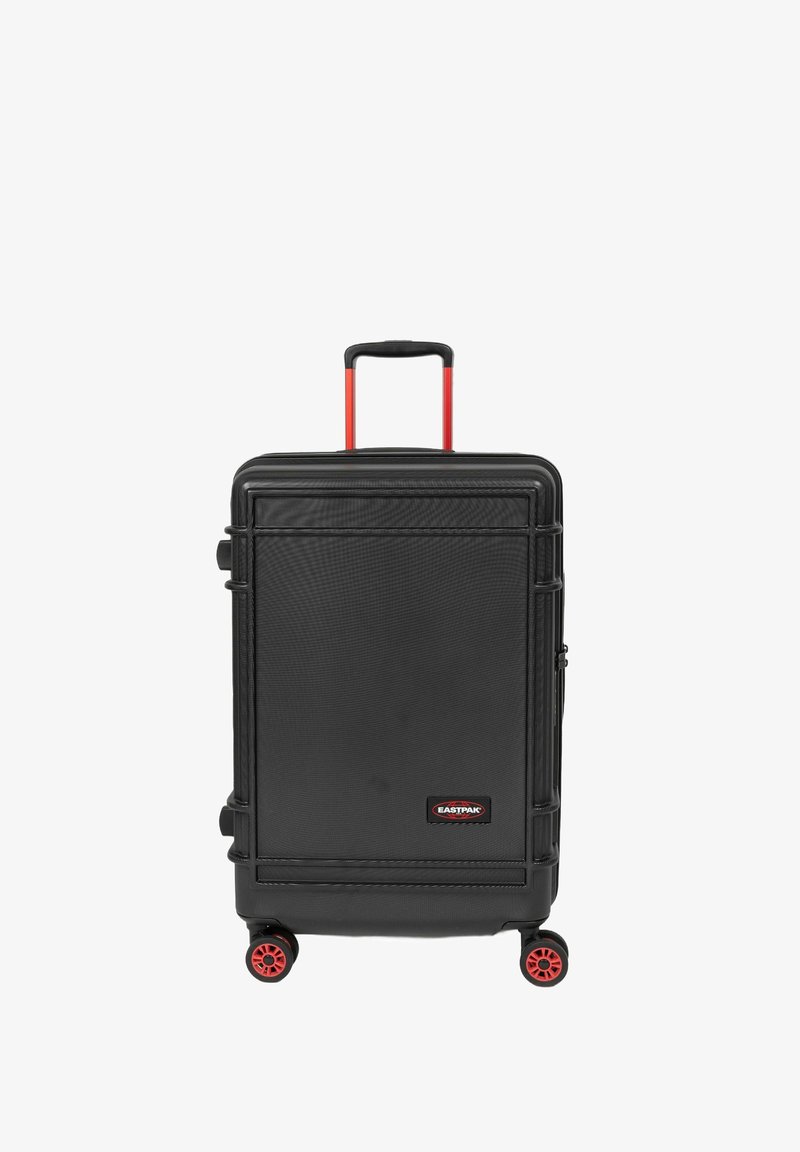 Valise rigide à roulettes noire avec une surface texturée, roues rouges et poignée rétractable. Présente le logo Eastpak à l'avant.
