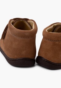 Bottes ankle en daim marron avec une forme arrondie, doublure intérieure douce et semelles en caoutchouc foncé ; présente des coutures le long des bords pour plus de durabilité.