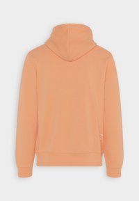 Haut à capuche couleur pêche en tissu doux, doté d'une poche kangourou et de poignets côtelés. Il comprend un capuchon avec cordon de serrage et un design minimaliste.