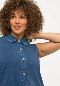 Ärmelloses Denim-Hemd mit Knopfleiste, klassischem Kragen und einer mittelblauen Farbe mit sanfter Textur.