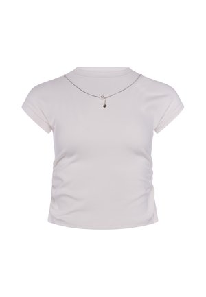 Crop top bianco aderente a maniche corte con lati arricciati e una sottile collana d'argento con perla e piccolo ciondolo nero.