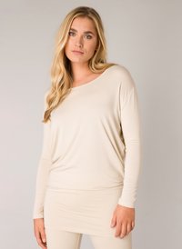Helle beige Langarmbluse mit lockerer Passform, aus weichem Material gefertigt. Verfügt über einen weiten Ausschnitt und einen drapierte Design, ideal zum Schichten.
