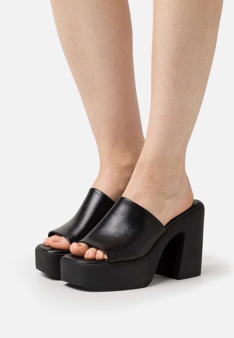 Svarte lær slidesandaler med åpen tå, tykk plattform og blokkheeldesign, med en glatt overflate og minimalt med maskinvare.