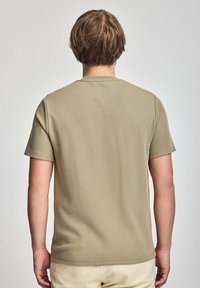 Olijfgroene t-shirt met korte mouwen en een ronde hals, gemaakt van een gestructureerde katoenmix. Eenvoudig ontwerp, geen zichtbare patronen of logo's.