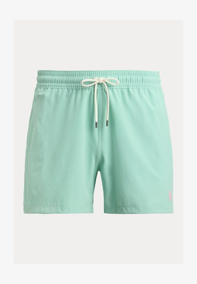 Πράσινα μαγιό βερμούδα μέντας με ελαστική μέση και λευκό κορδόνι, με ένα μικρό ροζ κεντητό λογότυπο στο αριστερό πόδι.