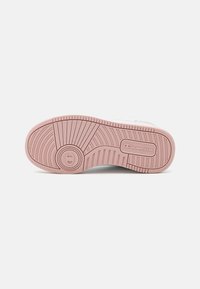 Suela de zapatilla blanca con una suela de goma rosa, que presenta surcos de tracción horizontales y verticales y un pequeño logo cerca del talón.