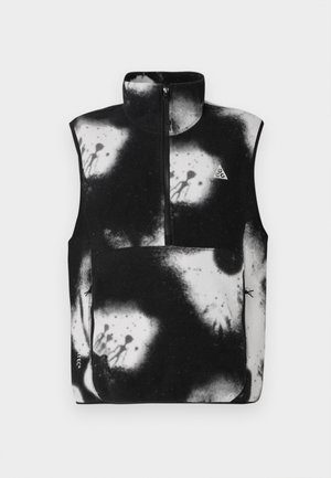 Vesta fără mâneci, alb-negru, cu guler înalt, fermoar frontal și un pattern abstract, cu stropi pe întreaga țesătură.