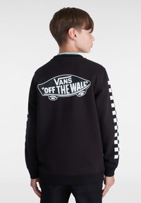 Sudadera negra con gráfico blanco "Vans Off the Wall" en la parte posterior y patrón a cuadros en las mangas; puños y dobladillo acanalados.