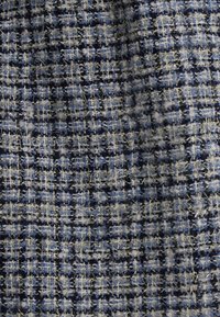 Tejido tejido con un patrón de cuadros azul, gris y blanco, que presenta hilos texturizados y acentos metálicos en toda su superficie.