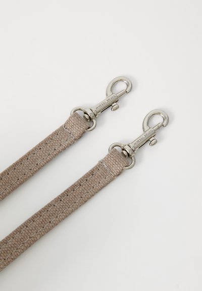 Sangle en tissu tissé beige avec des clips en métal argenté à chaque extrémité. Surface texturée avec des détails de couture le long des bords.