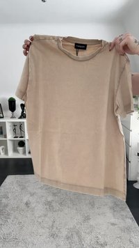 Beige t-paita, jossa on pyöreä kaula-aukko ja lyhyet hihat, suora helma ja logotagi takana kauluksessa.