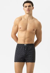 Černé boxerky s jemným bílým vzorem, elastickým pasem a pohodlným střihem. Materiál je měkký a prodyšný. Navrženo pro muže.