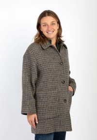 Cappotto di lana marrone con motivo a quadri, dotato di colletto, chiusura con bottoni e due tasche anteriori. Design ampio con forma dritta.