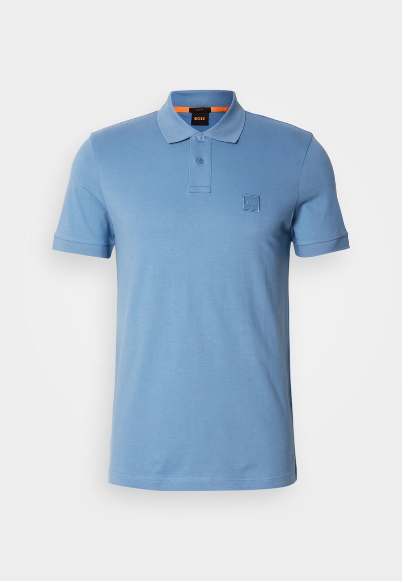 Polo de color azul claro, hecho de algodón suave, con un cuello clásico, tapeta de dos botones y parche de logo bordado en el pecho.