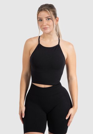 El conjunto de chándal negro cuenta con un top corto de tirantes finos y pantalones cortos de tiro alto. Está hecho de una tela elástica con una textura suave.
