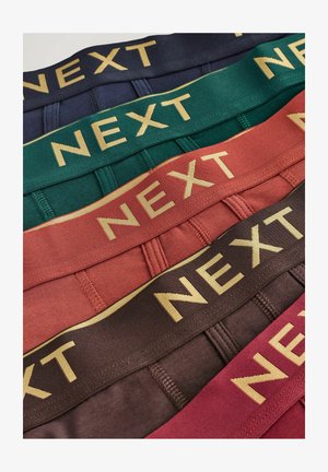 Collection of elastic waistbands in navy, green, red, and brown, each featuring the word "NEXT" in gold lettering across the front.