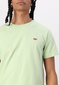 Lys grøn bomulds T-shirt med rund hals og korte ærmer. Har et lille rødt Levi's logo på venstre bryst. Blød tekstur.