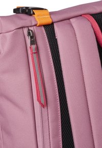 Primer plano de tela de mochila morada con cremallera vertical y detalles de correas en naranja y negro, resaltando la textura y los componentes de cierre.