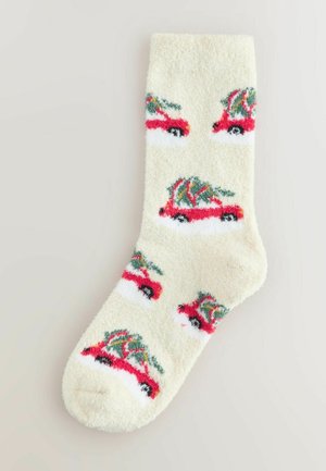 Puszyste kremowe skarpetki z powtarzającym się wzorem czerwonych samochodów i zielonych drzew. Miękka tekstura, zaokrąglony czubek i kontrastowe białe detale.