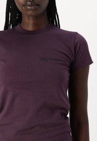 Ljubičasta majica s kratkim rukavima od mekanog pamuka s okruglim izrezom. Logotip "KARL LAGERFELD JEANS" u crnoj boji na lijevoj strani prsnog područja.